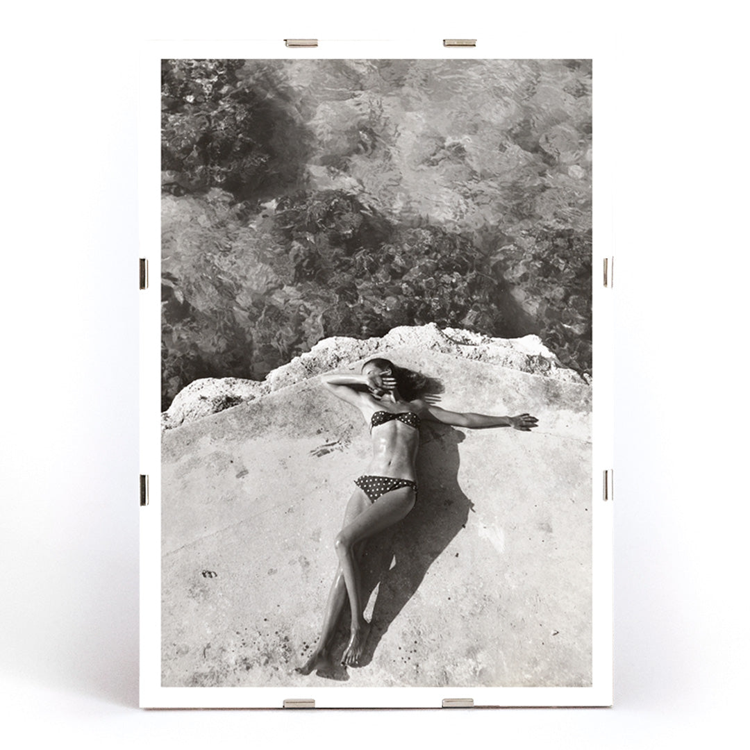 Woman in bikini lying on platform near water in Montego Bay Jamaica artwork by Nickerson Paine poster, framed and displayed in modern living room decor