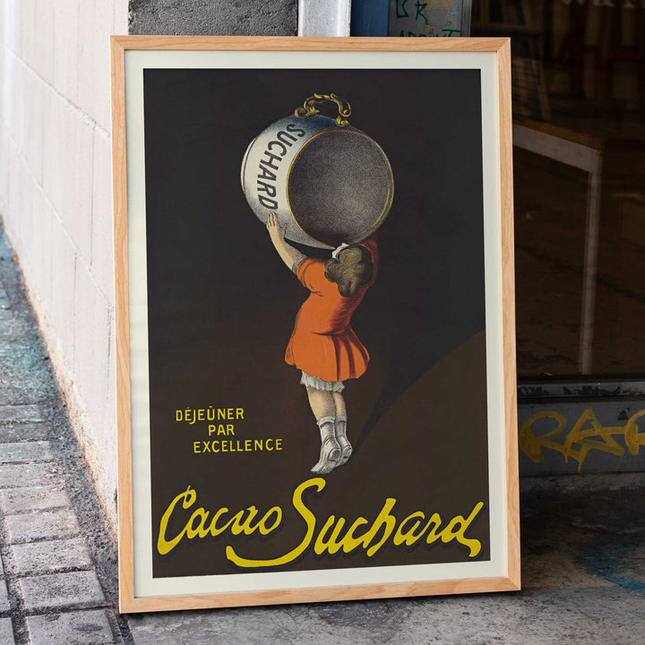 Leonetto Cappiello Cacao Suchard poster with girl lifting giant cocoa tin on dark background in orange dress and yellow lettering, framed and displayed in home decor