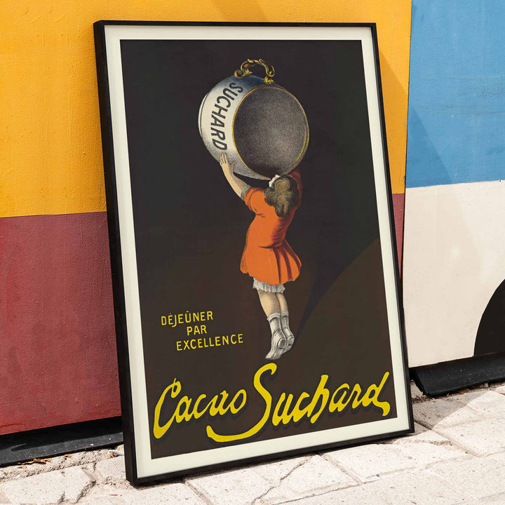Leonetto Cappiello Cacao Suchard poster with girl lifting giant cocoa tin on dark background in orange dress and yellow lettering, framed and displayed in modern living room decor