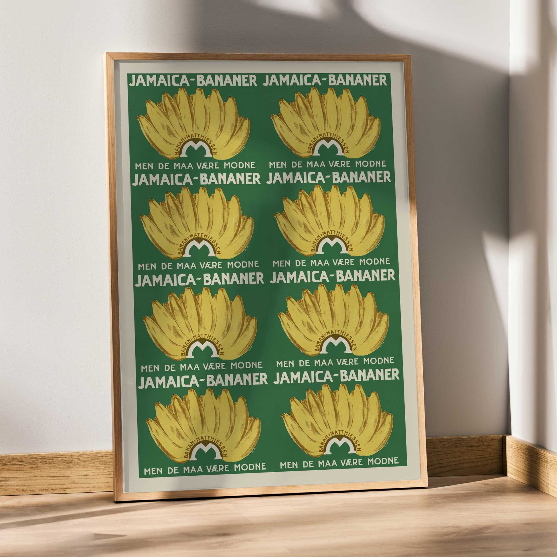 Jamaica Bananas poster with repeated ripe yellow banana bunches on a deep green vintage advertising design, framed and displayed in modern living room decor