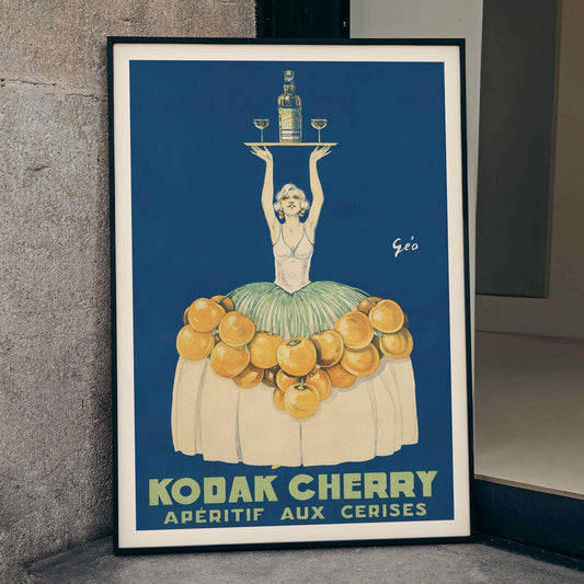 Géo Vermeire Kodak Cherry poster with woman in cherry-covered dress holding tray with bottle and two glasses, framed and displayed in home decor