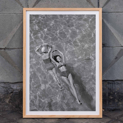 Fashion models in vintage bathing suits floating in a swimming pool artwork by Toni Frissell, framed and displayed in home decor