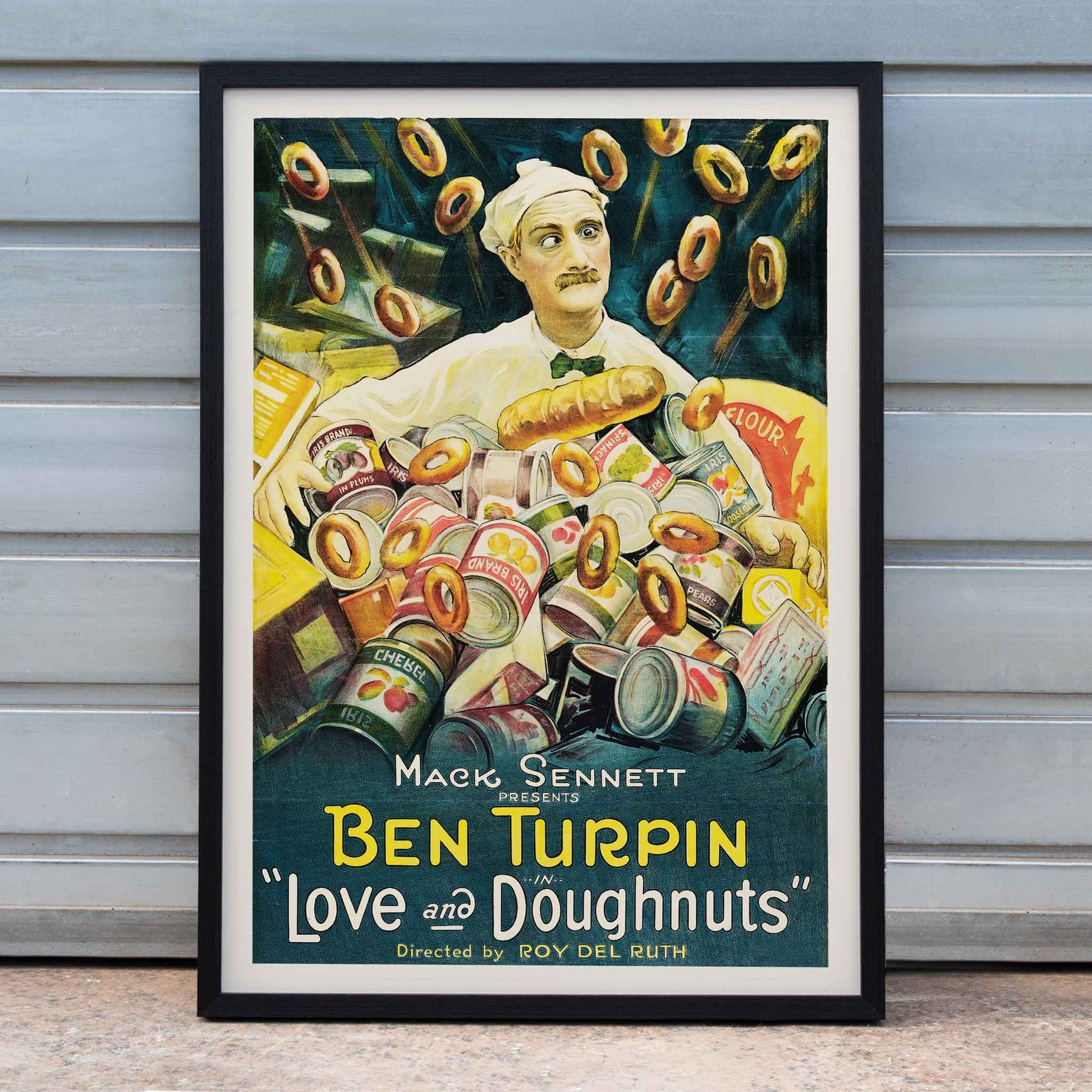 Love and Doughnuts artwork and film poster with baker and chef surrounded by flying doughnuts and canned goods, framed and displayed in home decor