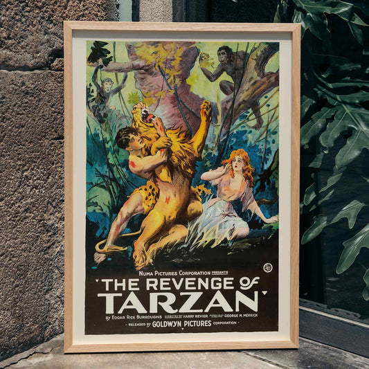 The Revenge of Tarzan poster art by Harry Revier showing a dramatic jungle scene with Tarzan wrestling a lion and a frightened woman watching, framed and displayed in home decor
