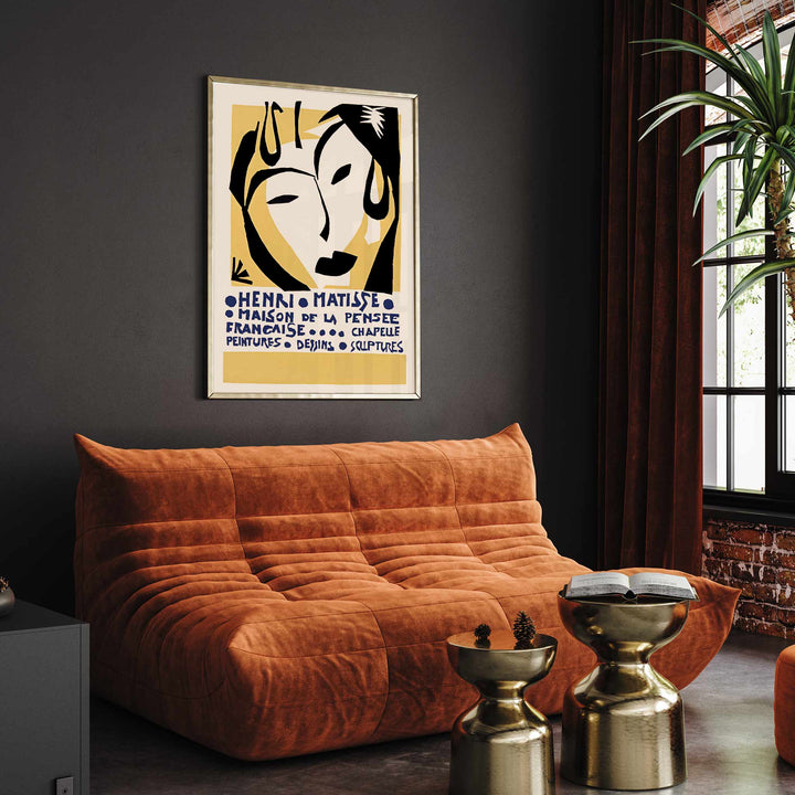 Henri Matisse Maison de la Pensee francaise poster with bold black abstract face shapes on warm yellow and cream minimalist design, framed and displayed in modern living room decor