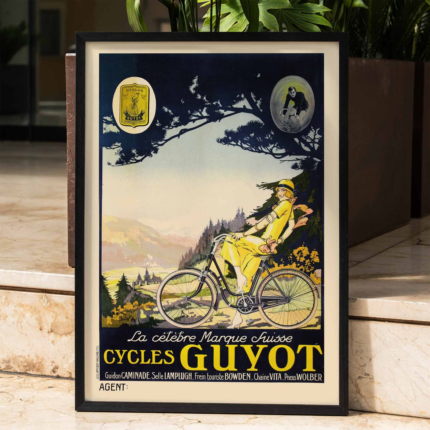 Woman in yellow riding a bicycle through a scenic landscape Cycles Guyot vintage poster artwork, framed and displayed in home decor