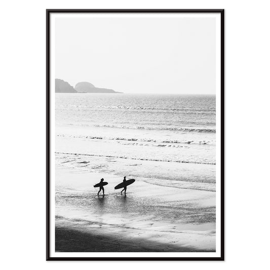 Black and white poster of surfers walking along the beach Surfers walking on the beach artwork, with black aluminium frame on white background