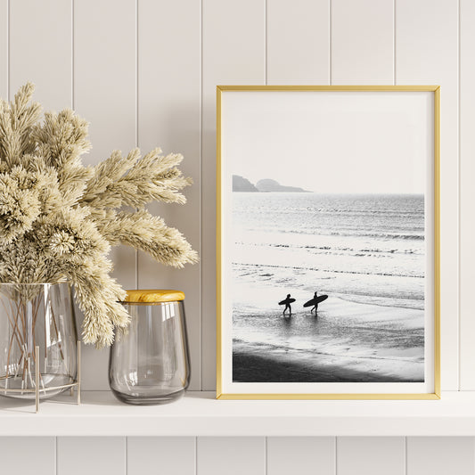 Black and white poster of surfers walking along the beach Surfers walking on the beach artwork, framed and displayed in home decor