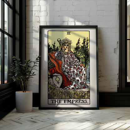 The Empress Tarot card by Rider Waite featuring a crowned woman seated on a throne in a lush natural setting holding a scepter with a crown of stars, framed and displayed in modern living room decor