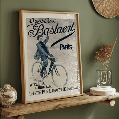 Vintage bicycle poster joyful man riding and waving on Cycles Bastaent Paris bike artwork by Charles Tichon, framed and displayed in home decor